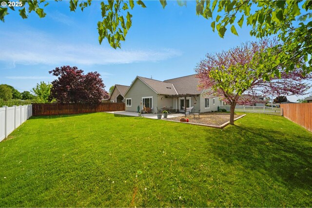 rear view of house featuring a yard, a fenced backyard, and a patio area