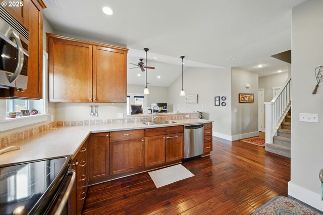 kitchen with a sink, a peninsula, dark wood-style floors, a ceiling fan, and appliances with stainless steel finishes