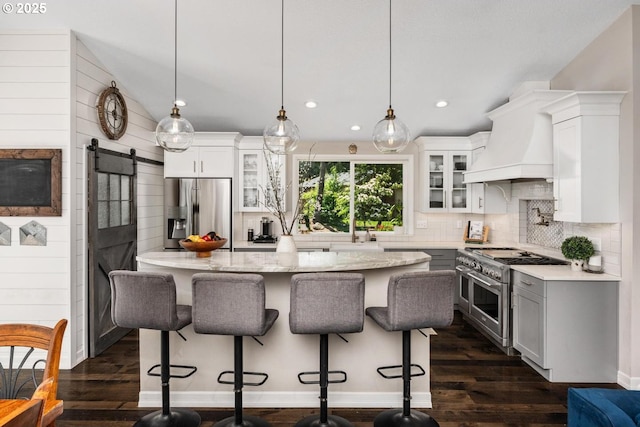 885 NW Torrey View Ln, Portland, OR 97229 - kitchen featuring appliances with stainless steel finishes, a barn door, decorative backsplash, glass insert cabinets, and a breakfast bar area