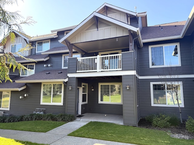 view of front of house with roof with shingles, board and batten siding, and a balcony