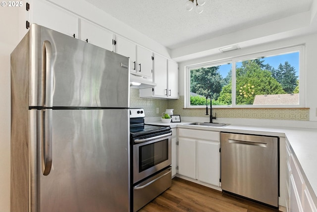 7631 SE Thompson Rd, Milwaukie, OR 97222 - kitchen featuring appliances with stainless steel finishes, under cabinet range hood, backsplash, light countertops, and white cabinets