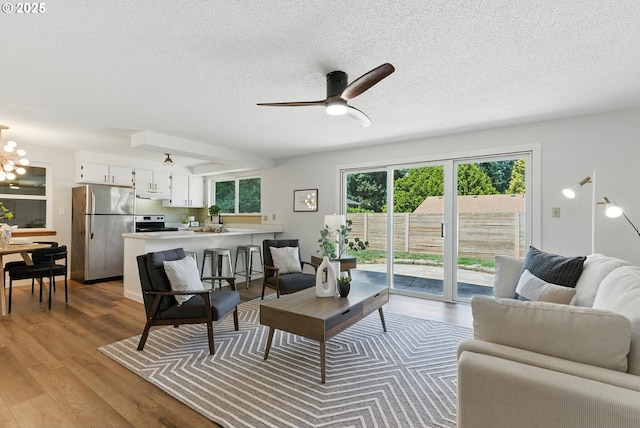 7631 SE Thompson Rd, Milwaukie, OR 97222 - living area with a textured ceiling, wood finished floors, a ceiling fan, and a chandelier