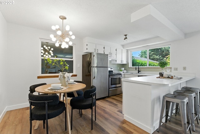 7631 SE Thompson Rd, Milwaukie, OR 97222 - kitchen featuring stainless steel appliances, a peninsula, a textured ceiling, white cabinetry, and dark wood-type flooring