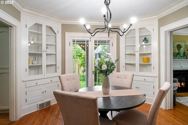 6116 SE 36th Ave, Portland, OR 97202 - dining room with a chandelier, ornamental molding, wood finished floors, and a lit fireplace