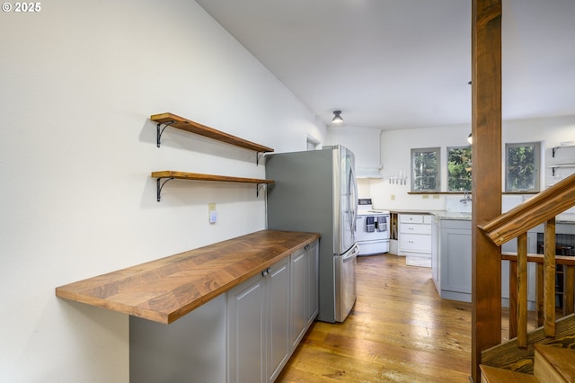 kitchen featuring light hardwood / wood-style flooring, stainless steel fridge, wooden counters, gray cabinets, and electric range