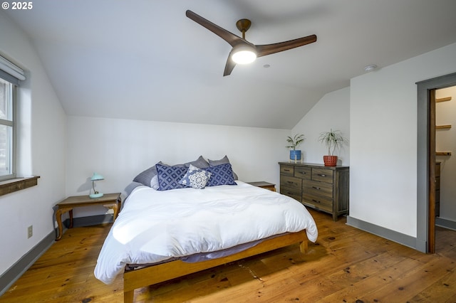 bedroom with ceiling fan, wood-type flooring, and lofted ceiling