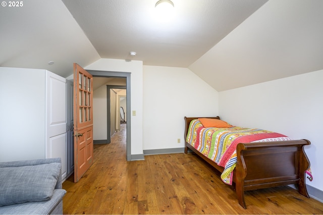 bedroom with wood-type flooring and vaulted ceiling