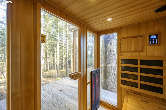 doorway to outside featuring wooden ceiling and wood walls