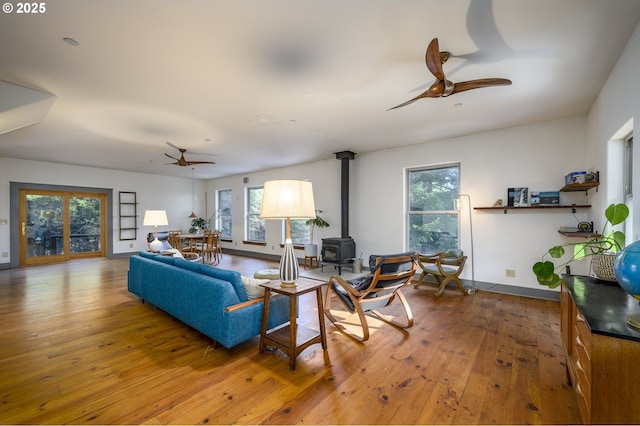 living room with a wood stove, hardwood / wood-style floors, and ceiling fan