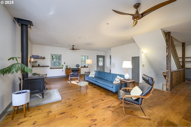 living room featuring hardwood / wood-style floors, ceiling fan, and a wood stove