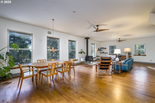 dining space with a wood stove, hardwood / wood-style floors, and ceiling fan