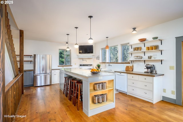 kitchen featuring white cabinetry, stainless steel fridge, a center island, and white dishwasher