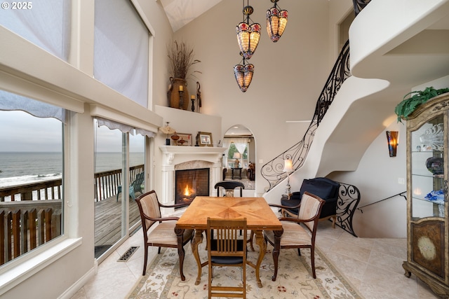 dining space featuring a water view, light tile patterned floors, and high vaulted ceiling