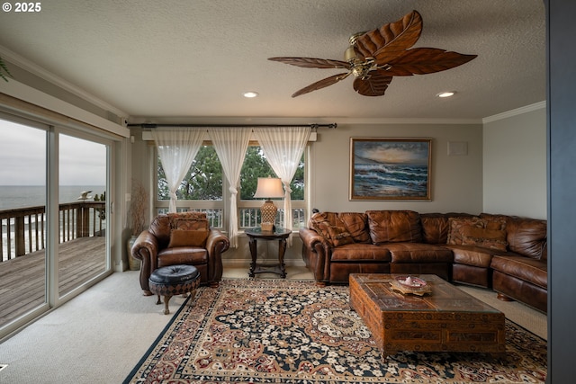 living room featuring carpet floors, ornamental molding, ceiling fan, a water view, and a textured ceiling