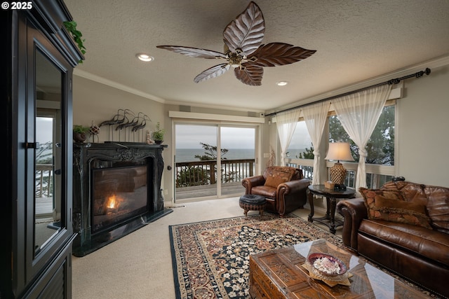 living room featuring crown molding, ceiling fan, carpet flooring, a fireplace, and a textured ceiling