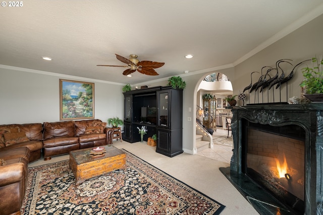 living room with crown molding, ceiling fan, a premium fireplace, and light carpet