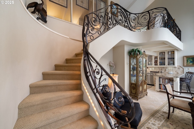 staircase featuring a towering ceiling and tile patterned floors