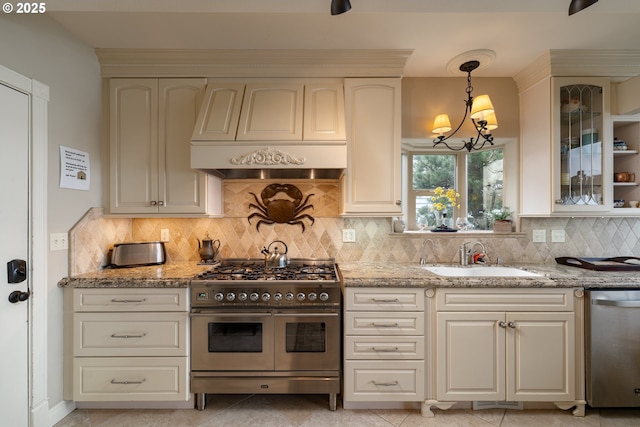 kitchen with sink, custom exhaust hood, light stone counters, decorative light fixtures, and appliances with stainless steel finishes