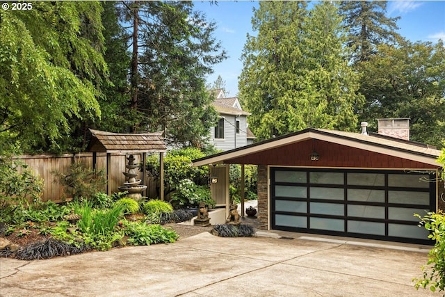 view of front facade featuring driveway, a garage, fence, and a chimney