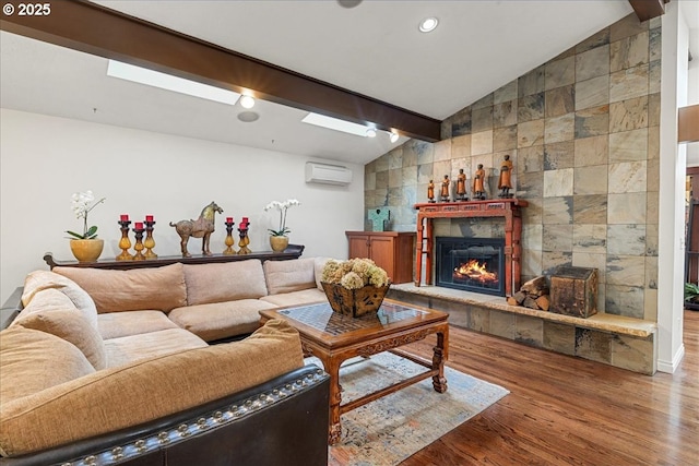 living area featuring an AC wall unit, wood finished floors, and a glass covered fireplace