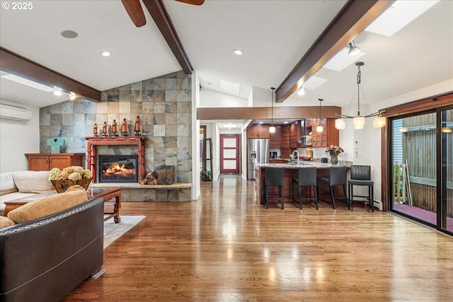 living room with wood finished floors, a glass covered fireplace, a ceiling fan, and a wall unit AC