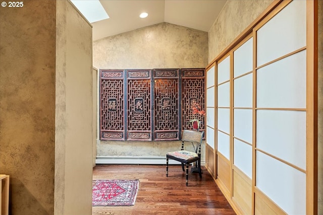 hallway with lofted ceiling, wood finished floors, a baseboard radiator, and a skylight