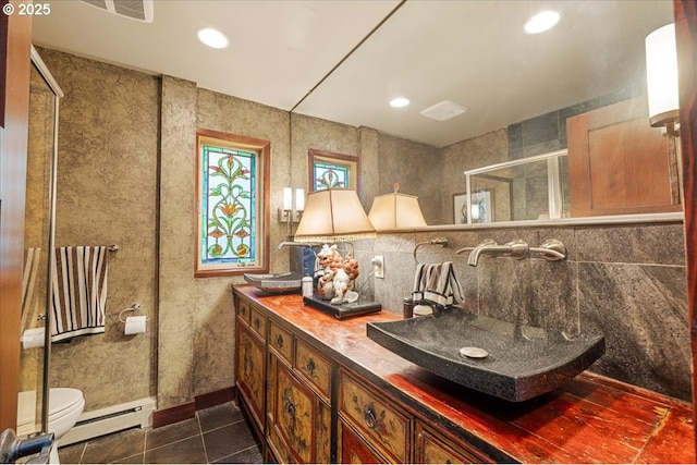 bathroom featuring baseboard heating, a shower stall, toilet, tile patterned floors, and double vanity
