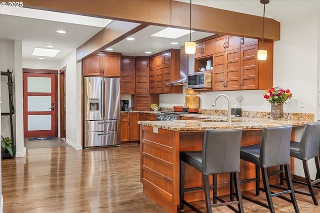 kitchen featuring appliances with stainless steel finishes, open shelves, a peninsula, brown cabinets, and recessed lighting
