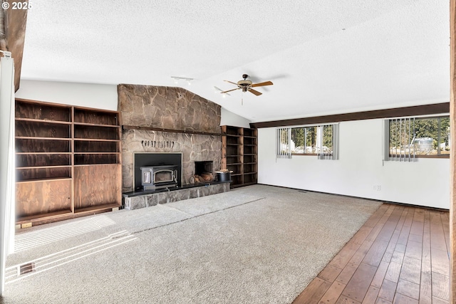 19826 NE 154th St, Brush Prairie, WA 98606 - unfurnished living room featuring ceiling fan, lofted ceiling, a wood stove, and a textured ceiling