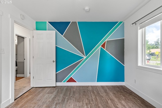 empty room with wood finished floors, a smoke detector, plenty of natural light, and baseboards
