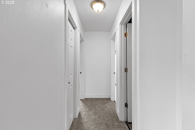 hall with dark colored carpet and baseboards