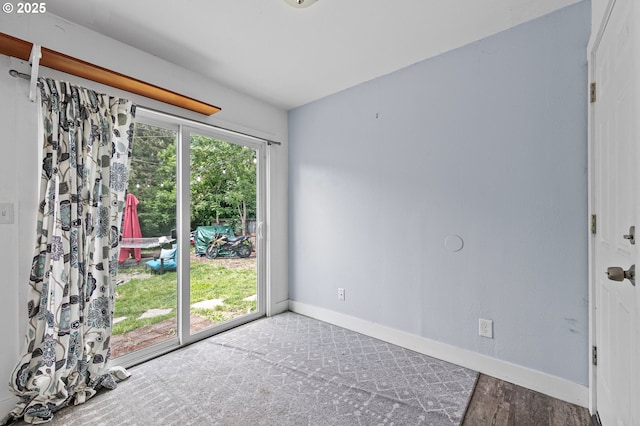 spare room with baseboards and wood finished floors