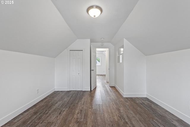 bonus room with dark wood-type flooring, baseboards, and vaulted ceiling
