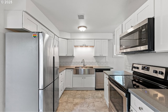 kitchen featuring appliances with stainless steel finishes, a sink, white cabinetry, and tasteful backsplash