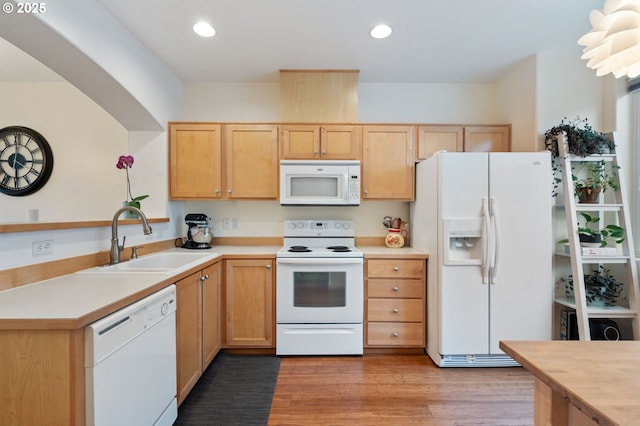 kitchen with light brown cabinets, light countertops, white appliances, and a sink