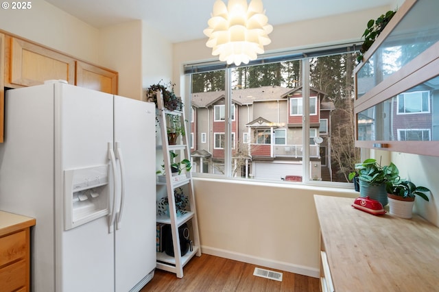 kitchen featuring visible vents, wood finished floors, an inviting chandelier, light countertops, and white fridge with ice dispenser