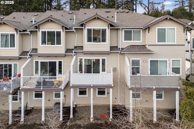 back of house with a shingled roof and central AC unit