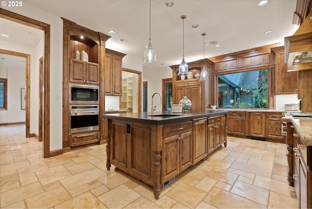 kitchen featuring built in microwave, sink, pendant lighting, a center island with sink, and oven