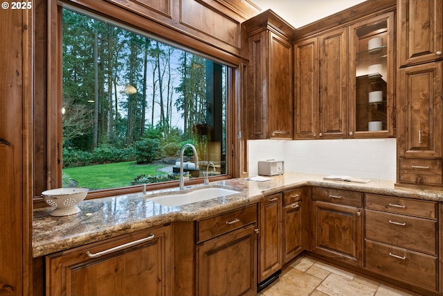 kitchen featuring light stone countertops, tasteful backsplash, and sink