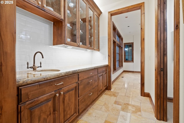 bar with light stone countertops, decorative backsplash, and sink