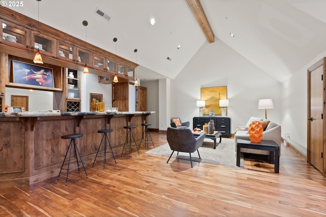 bar featuring hardwood / wood-style floors, beam ceiling, hanging light fixtures, and high vaulted ceiling