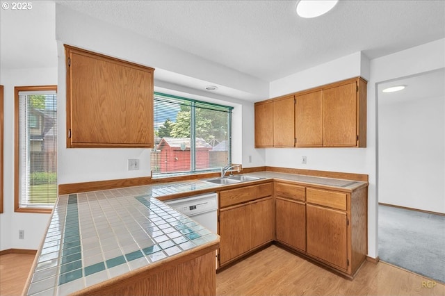 5868 NW Landing Dr, Portland, OR 97210 - kitchen featuring tile countertops, a sink, light wood-type flooring, brown cabinets, and a textured ceiling
