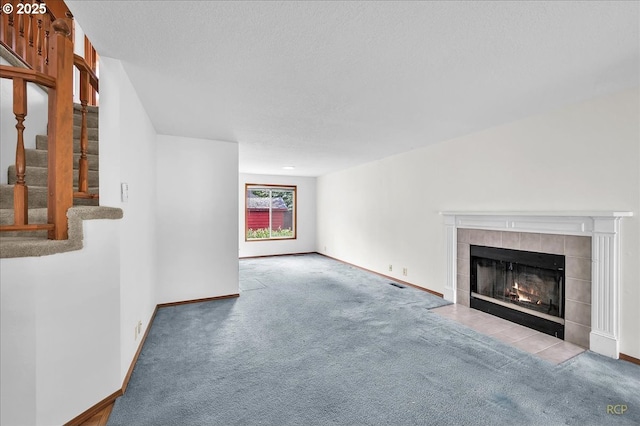 5868 NW Landing Dr, Portland, OR 97210 - unfurnished living room featuring carpet, stairs, baseboards, a tile fireplace, and a textured ceiling