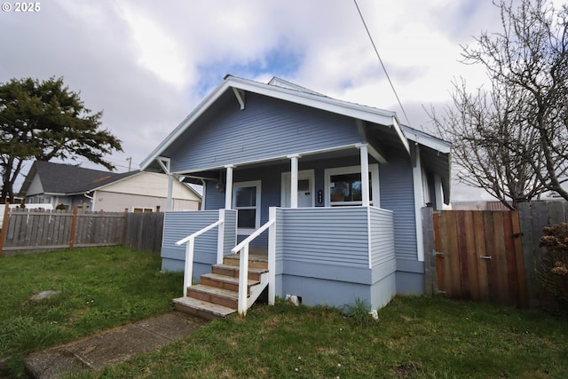 bungalow-style home featuring a porch, fence, and a front lawn