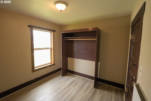 unfurnished bedroom with radiator, baseboards, a closet, and light wood-type flooring