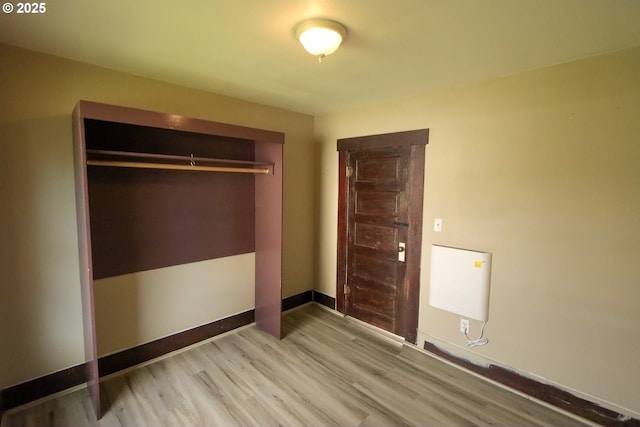 unfurnished bedroom with a closet, light wood-style flooring, and baseboards