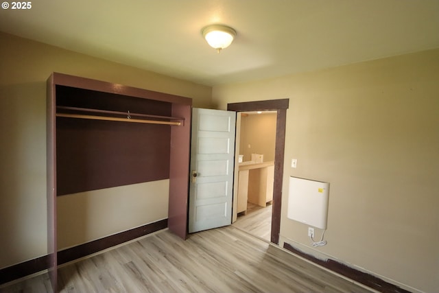 unfurnished bedroom featuring a closet, baseboards, and light wood-style floors