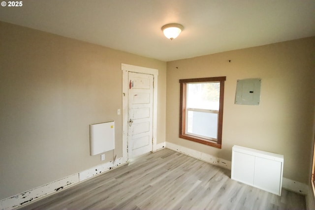 unfurnished room featuring electric panel, baseboards, and wood finished floors