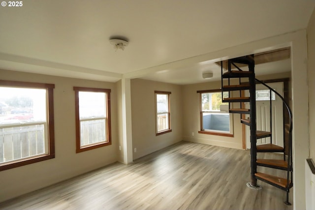 unfurnished room with stairway, baseboards, and light wood finished floors