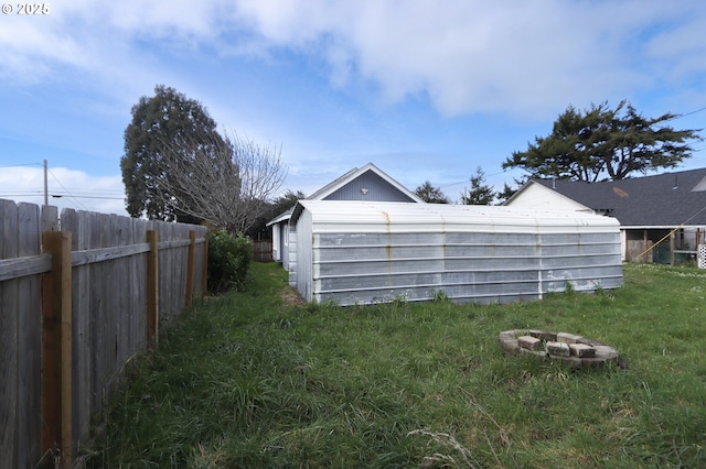 view of yard with an outbuilding, an outdoor fire pit, and fence